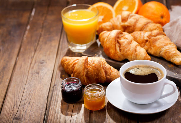 breakfast with cup of coffee and croissants breakfast with cup of coffee, croissants, orange juice and fruit jam on wooden table croissant stock pictures, royalty-free photos & images