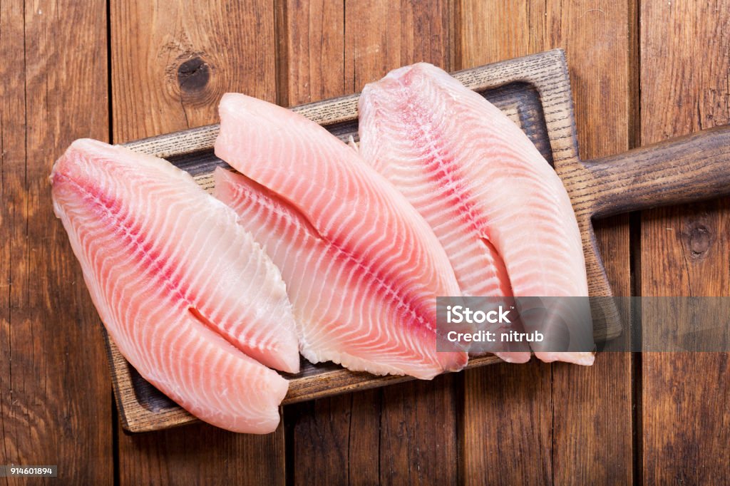 filet de poisson frais sur planche de bois - Photo de Tilapia libre de droits