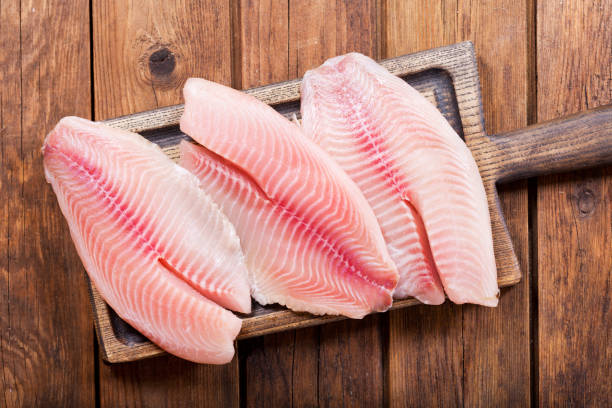 木��の板に新鮮な魚の切り身 - prepared fish tilapia fillet seafood ストックフォトと画像