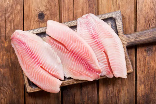 fresh fish fillet on wooden board, top view