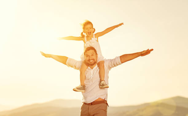 istock father's day. child daughter sits on her dad shoulders outdoors on a summer 914602140