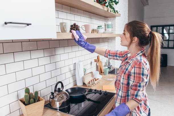 istock Woman in rubber gloves cleaning kitchen cabinet 914602858