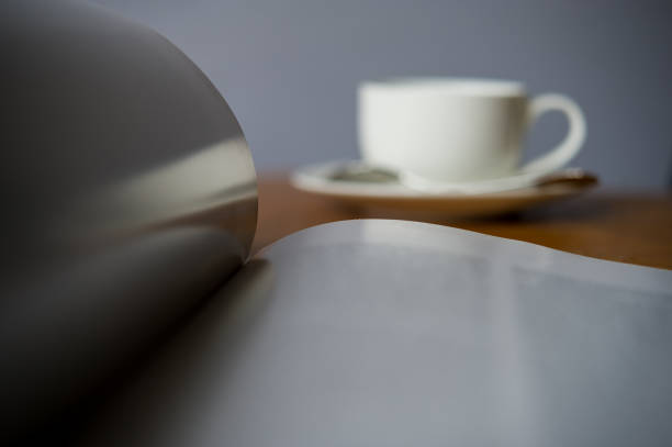 open magazine on a blurry background with a cup of coffee. open magazine on a blurry background with a cup of coffee.The magazine is on the desk in the office. food sample cups stock pictures, royalty-free photos & images