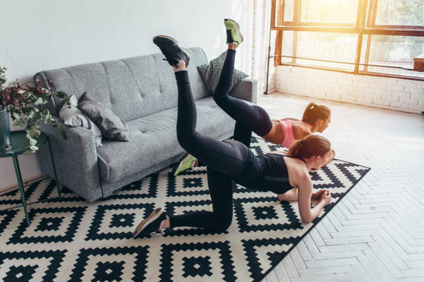 istock Two sportive female friends doing butt toning exercise performing donkey kicks at home 914612088