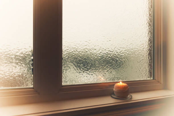 istock Burning candle and frosted window in hazy light 914612964