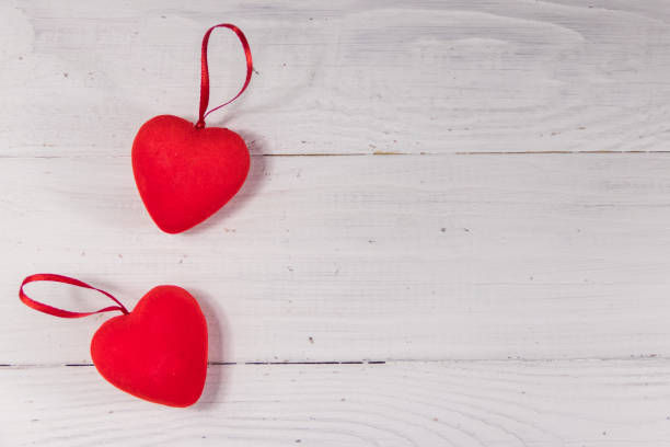istock Two red hearts on white wooden background 914613760