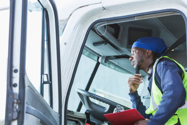 Mature black man driving semi-truck A mature black man in his 40s driving a semi-truck. He is sitting in the truck cab holding a clipboard, with the door open. do rag stock pictures, royalty-free photos & images