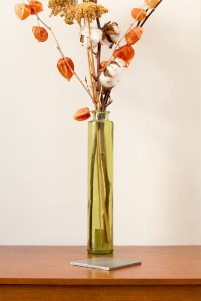 istock Cylindrical Vase with Dried Blooms and Square Coaster on Wooden Surface 914629846