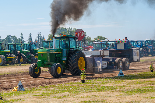 Mon Denmark - July 6. 2014: Green tractor pulling the sled with lot of smoke at a Tractor pulling competition