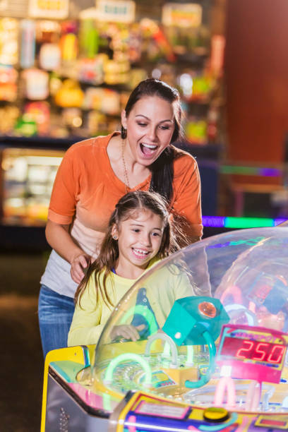 istock Mother and daughter playing game in amusement arcade 914633098