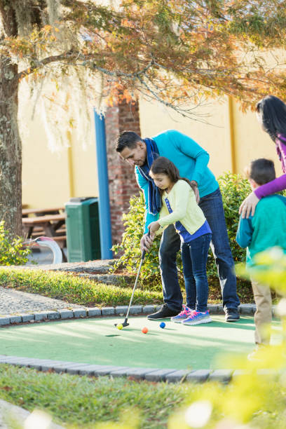 istock Family playing miniature golf, father helping daughter 914633402