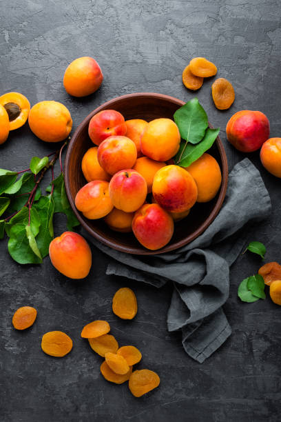 frische aprikosen mit blätter und getrocknet in schüssel auf tisch - dried apricot stock-fotos und bilder
