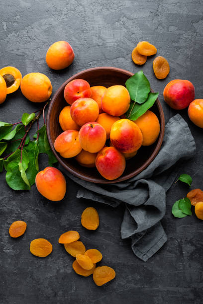 Fresh apricots with leaves and dried in bowl on table Fresh apricots with leaves and dried in bowl on table apricot stock pictures, royalty-free photos & images