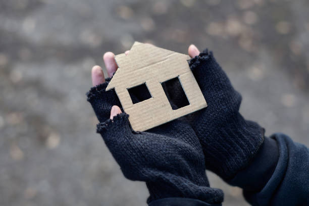 young homeless boy holding a cardboard house young homeless boy holding a cardboard house homelessness photos stock pictures, royalty-free photos & images