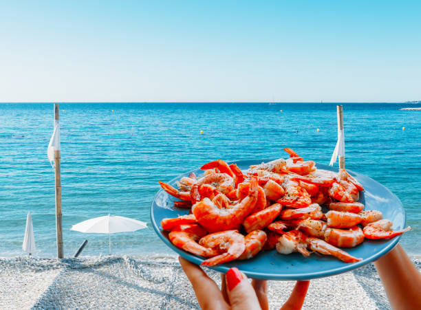 Prawns or shrimp on a plate at edge of beautiful Mediterranean beach - composite