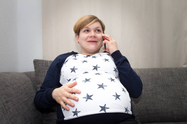 telefoniert schwangere frau mit einem smartphone - human pregnancy flash fotografías e imágenes de stock