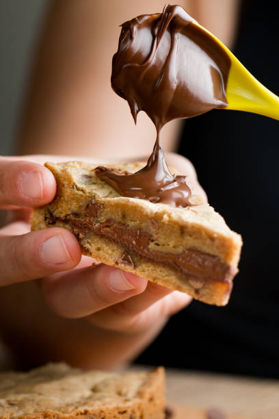 woman holding a hazelnut cookie slice - chocolate spread imagens e fotografias de stock