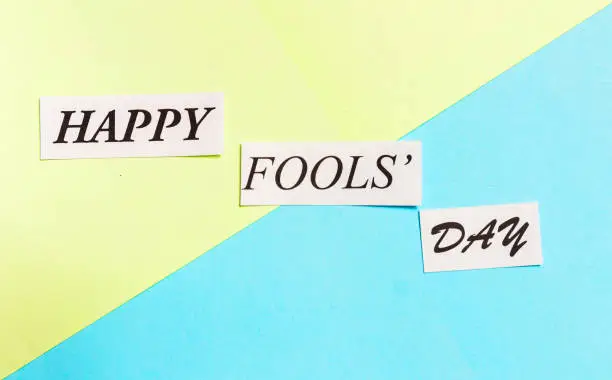 Photo of Happy Fools Day printed phrase on green blue background