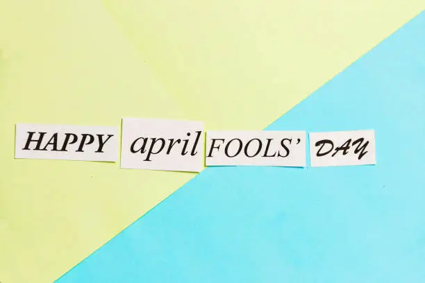 Photo of Happy April Fools Day printed phrase on green blue background