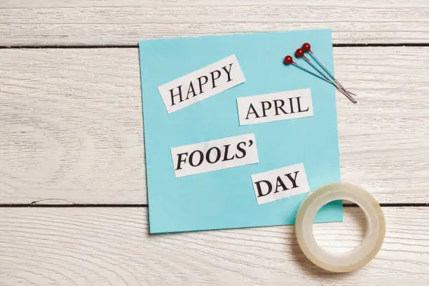 Photo of Happy April Fools Day phrase on wooden background