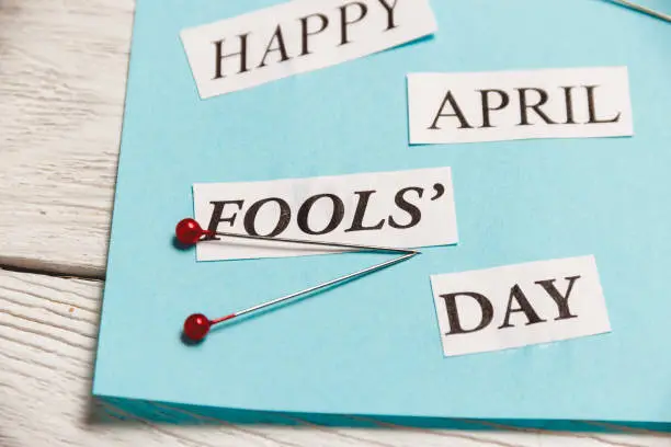 Photo of Happy April Fools Day phrase on wooden background