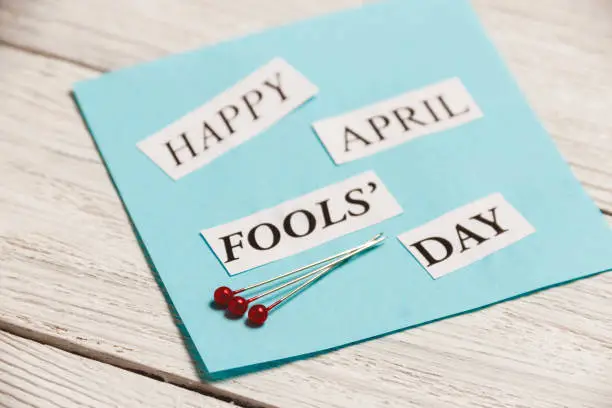 Photo of Happy April Fools Day phrase on wooden background