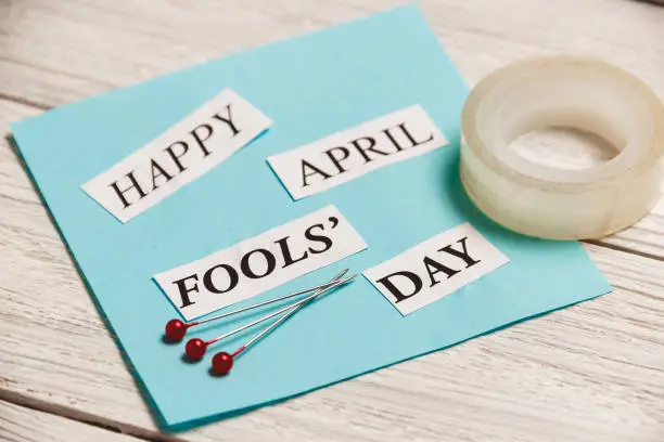 Photo of Happy April Fools Day phrase on wooden background