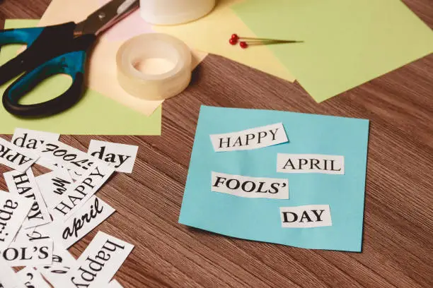 Photo of Happy April Fools Day phrase on wooden background