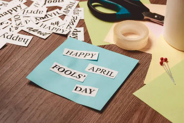 Photo of Happy April Fools Day phrase on wooden background