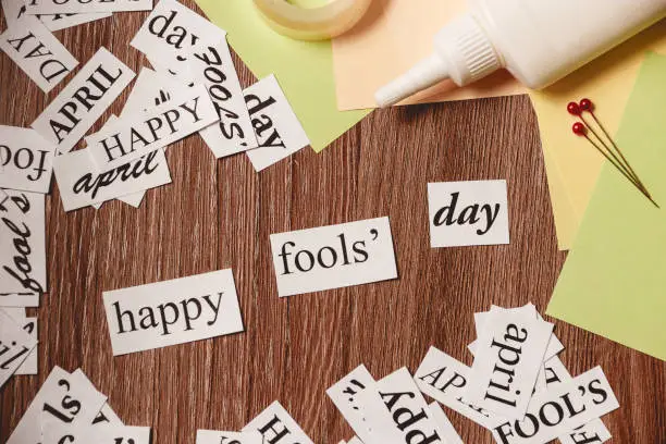 Photo of Happy Fools Day phrase on wooden background