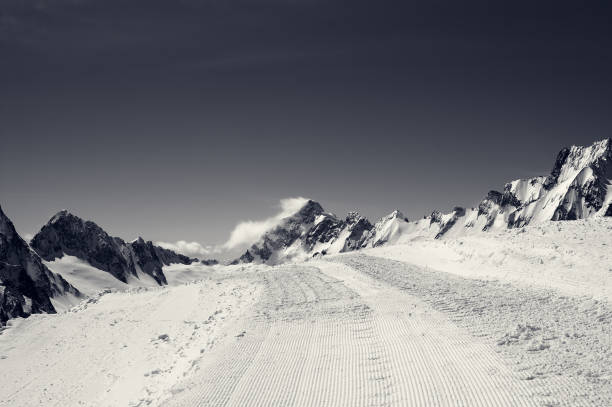 istock Black and white snowy road with trace from snow groomer 914679408