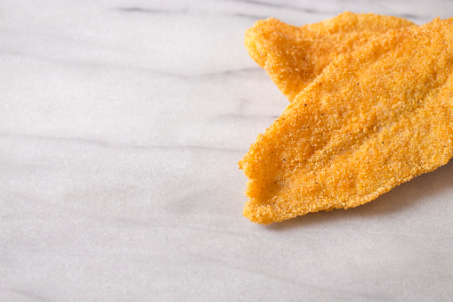 Two Fresh Fish Fillets Fried and Isolated on a Marble Slab
