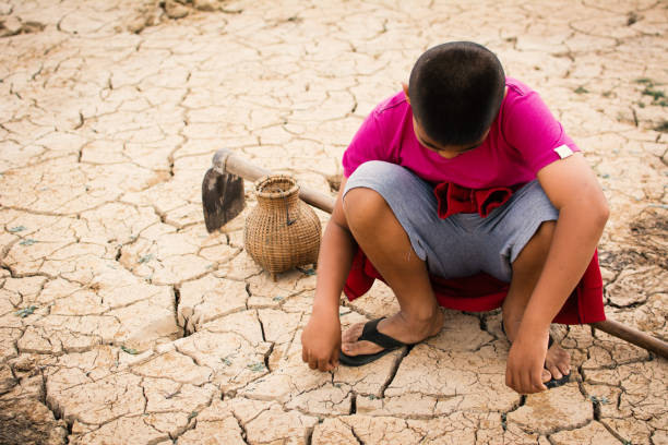 istock High Angle View Of Boy Crouching On Cracked Field 914700426