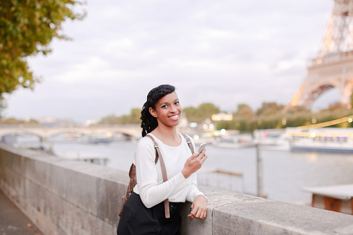 Smiling business woman standing on bridge and using smartphone
