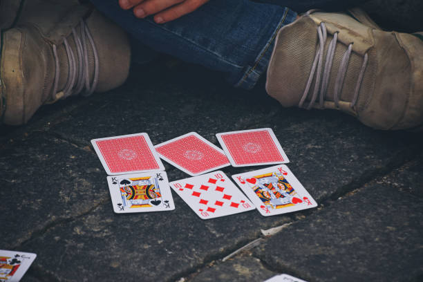 istock Low Section Of Man Playing Cards While Sitting On Street 914706814