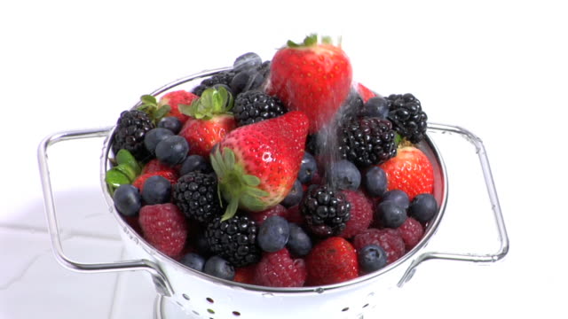Water pouring over colander of fresh berries