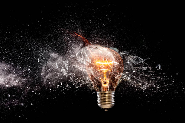 istock Close-Up Of Broken Illuminated Light Bulb Against Black Background 914711430
