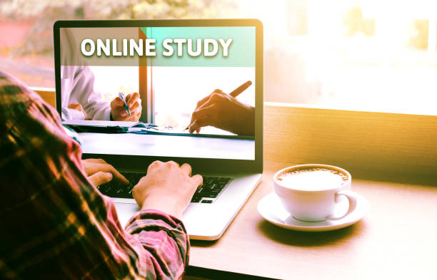istock Rear and shoulder view of student using laptop with online learning concept at coffee shop. 914729884