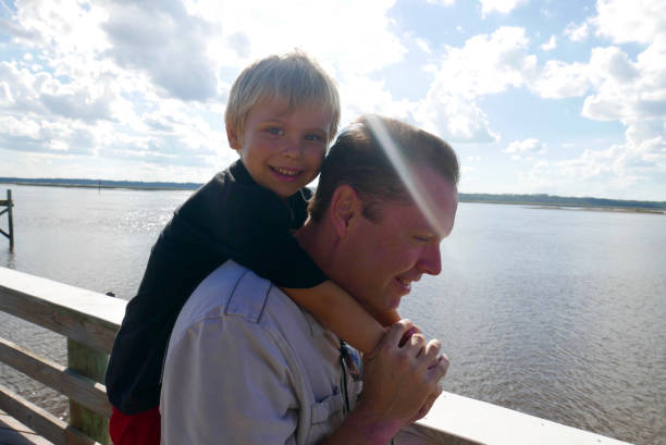 istock Father carrying his son on his back, bright sun 914732052