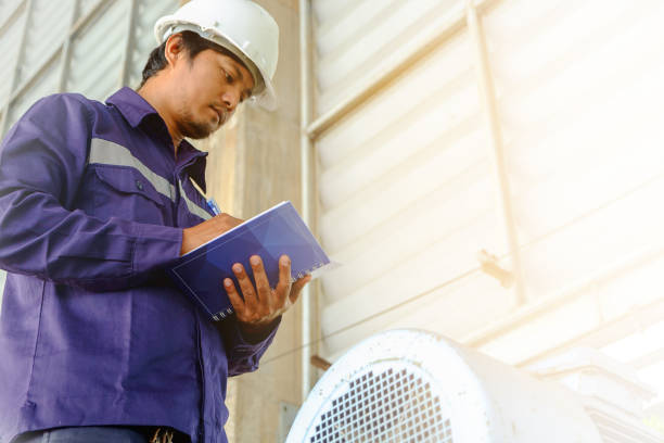 istock Asian engineer or technician in safety uniform and white helmet checking motor gear machinery equipment  and writing data on notebook with sun light effect for industrial concept 914739270