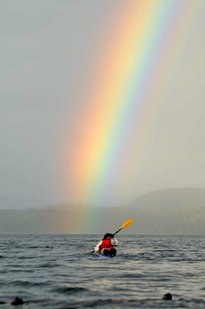 A kayak-er paddles among small islands after a rain storm in the Canadian Pacific Northwest