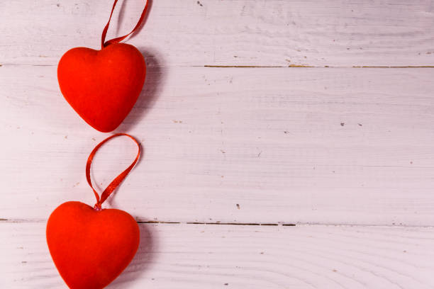 istock Two red hearts on a white wooden table. Top view 914747284