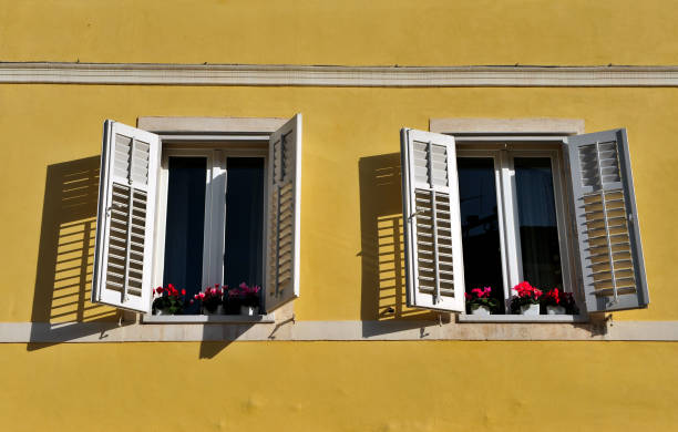 istock Two open windows with flowers in old town 914750342
