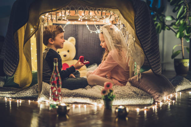 istock Cute little boy making a surprise for his girlfriend while proposing her in a tent. 914751342
