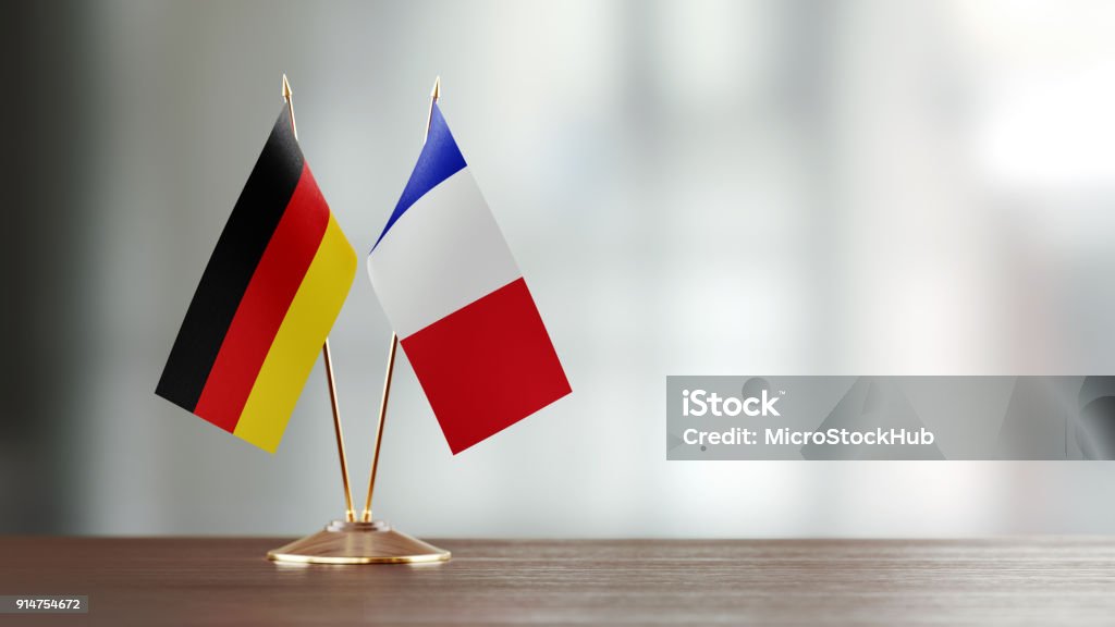 German And French Flag Pair On A Desk Over Defocused Background German and French flag pair on desk over defocused background. Horizontal composition with copy space and selective focus. Germany Stock Photo