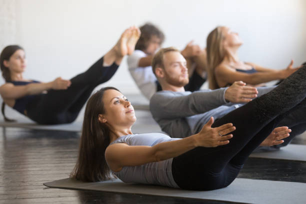 gruppo di giovani sportivi in posa in barca - pilates foto e immagini stock