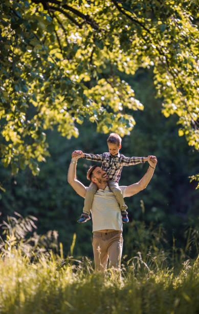 istock Happy father carrying his son on shoulders during spring day in the park. 914755654