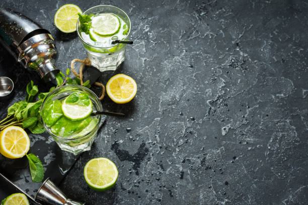 istock Mojito cocktail with lime and mint in highball glass on a stone table. Drink making tools and ingredients for cocktail. Copy space 914759800