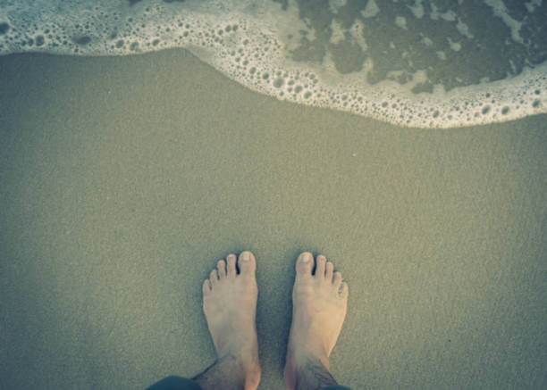 istock feet with wave on sandy beach top view 914770998
