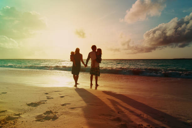 happy family with two kids walking at sunset tropical beach